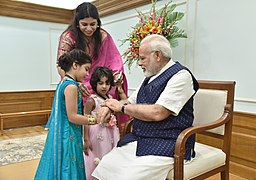 नवी दिल्ली इथे रक्षा बंधन दिनी पंतप्रधान नरेंद्र मोदी यांच्या हातावर छोटी मुली 'राखी' बांधत आहे