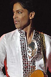 Prince olhando para a direita, vestindo uma camisa branca.