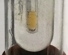 Sampel kecil dari fluorin cair berwarna kuning pucat yang dikondensasi dalam nitrogen cair