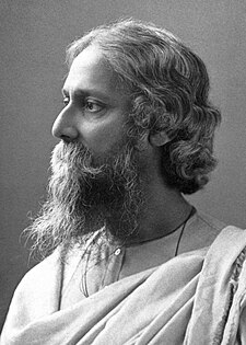 Late-middle-aged bearded man in white robes looks to the left with serene composure.