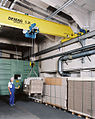 Circa 2010 Demag Overhead crane and hoist (device) being used in typical machine shop. The hoist is operated via a wired pushbutton station, known as a pendant, to move the system and the load in any direction