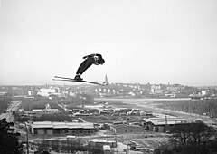 25 januari 1953, med backhoppning i Hammarbybacken. Utsikt mot Södra Hammarbyhamnen och östra Södermalm. Norrmannen Odd Westby hoppar.