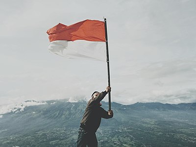 Seorang pendaki tengah mengibarkan bendera Indonesia di puncak Gunung Penanggungan, Jawa Timur