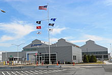 Pabrik Boeing di Ridley Park, Pennsylvania – sebuah bangunan dengan dinding aluminium, tempat parkir di depan, dan tiang bendera dengan tujuh bendera
