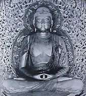 Vista frontal de una estatua con las piernas cruzadas, en postura de meditación (Dhyāna Mudrā) con ambas manos obre el regazo y las palmas hacia arriba.