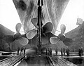 Shipyard employees photographed under the Olympic's propellers after their installation