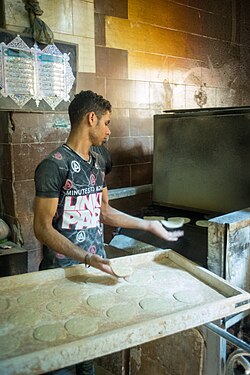 A young man putting discs of bread into the oven in the Islamic Cairo section of Cairo, Egypt.