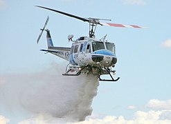 Un Bell 205 dels bombers llançant aigua per apagar un foc