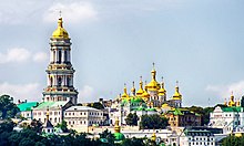 Widok frontowy na Ławrę Peczerską z oddali. Po prawej stronie widać kompleks sześciu wież z zabudową, po prawej dominuje strzelista wieża zakończona złotą kopułą.