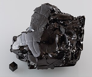 Uma grande amostra de carbono vítreo, com um peso de cerca 570 g, bem como um cubo de 1 cm³ de grafite para comparação. (definição 4 432 × 3 674)