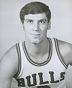 A black-and-white photo of a white man wearing a white uniform that says "Bulls" on it.