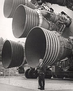 مُهندس الصواريخ ڤيرنر ڤون براون بمركز الفضاء والصواريخ الأمريكي يقف بجانب خمس مُحرِّكات F-1 والتي استخدمت في المرحلة الأولى لساتورن 5 ضمن برنامج أپولو والذي أدَّى في النهاية لهبوط أوَّل إنسان على سطح القمر