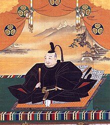 Tranh vẽ một một người đàn ông châu Á cổ xưa đang ngồi và ăn mặc lộng lẫy.