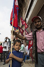 A man and his son pose with the Nepal national flag outside Durbar Square
