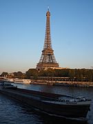 A barge sailing past the Eiffel Tower at sunset