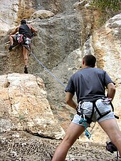 Un grimpeur est assuré en tête sur une falaise