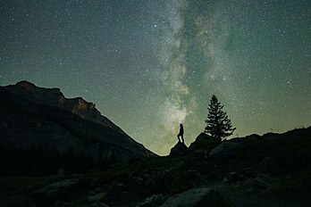 Um homem procurando estrelas cadentes com a Via Láctea ao fundo durante as Perseidas no lago Oeschinen, Suíça. As Perseidas são uma prolífica chuva de meteoros associada ao cometa Swift-Tuttle, geralmente visível de meados de julho até o final de agosto. Os meteoroides são chamados de Perseidas porque aparecem na direção geral da constelação de Perseu e, em tempos mais modernos, têm um radiante que faz fronteira com Cassiopeia e Camelopardalis. (definição 7 612 × 5 075)