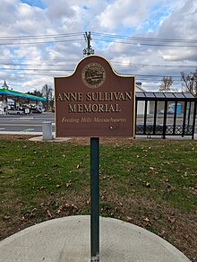 Sign in a park that says «Anne Sullivan Memorial, Feeding Hills, Massachusetts, Funded by the Community Preservation Act Committee» under the Town of Agawam seal.