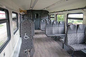 Салон с серыми сиденьями и спинками для инвалидов, коричневым полом и чёрными торцевыми стенками
