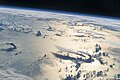 25. Látkép a Nemzetközi Űrállomásról a Filippínó-tenger felett. A délutáni napfény széles sávban tükröződik a tengeren. A horizont felé a távolban nagyrészt felhőréteg fedi a Fülöp-szigetek északi részét. A kép jobb alsó részén két nagy zivatarfelhő emelkedik egymás mellett, közel 100 kilométerre déli irányba elnyúlva (javítás)/(csere)