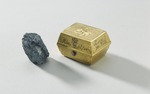 En gulddosa med blykula, som sägs vara den muskötkula som hittades i Karl XII:s halsduk efter slaget. Utställt på Livrustkammaren.