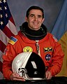 Leonid Kadenyuk de la NASA, observe diferentes tonos de azul en el parche y en la bandera detrás (1997)