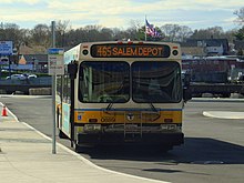A city bus waiting at a sidewalk