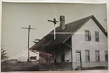 A black-and-white postcard of a two-story wooden railway station
