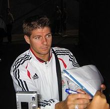 Gerrard in a white adidas shirt signing autographs