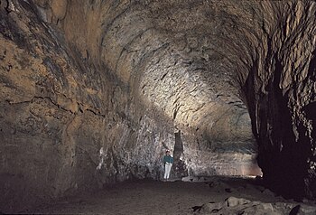 A hiker stands under the arched ceilings of the Lava River Cave, which was formed from a lava flow at Newberry Volcano