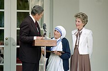 President and Mrs. Ronald Reagan with Mother Teresa, standing at a microphone