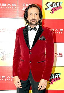 Actor Kay Kay Menon standing, dressed in a red and black tuxedo.