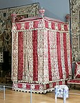 Baroque four-poster bed from the Château d'Effiat; c.1650; natural walnut, chiselled Genoa silk velvet and embroidered silks; 295 cm; Louvre[55]