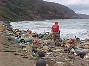 ハワイの海岸に打ち寄せられたゴミの山。人類が日常的に川や側溝などに捨てているゴミが、ひとめぐりして結局 海岸にたどりつく。（商品に印刷されている文字などによって）ハワイの海岸に打ち寄せられるゴミの数割は日本人が出したゴミであることが知られている。