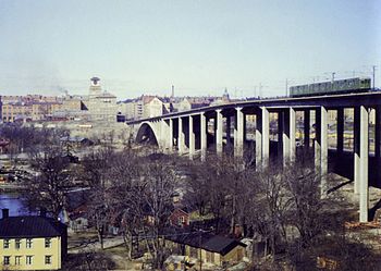 Skanstullsbron då och nu sedd från Skanskvarn. På bilden till vänster syns en av Stockholms äldre gröna tunnelbanevagnar och på bilden till höger kör den nya vagnen av typ C20 över bron. Sedan 1946 har bilden förändrats en hel del; 1984 invigdes ytterligare en högbro, Johanneshovsbron, och 2002 tillkom slutligen Fredriksdalsbron för Tvärbanan (som syns i förgrunden). På bilden från 1953 reser sig Åhléns Söders kända torn på Södermalms sida. Tornet och byggnaden finns kvar men döljs nu av Johanneshovsbrons höga spann. Byggnaden längst ner till vänster hör till Sundsta gård. Färgfotografiet från 1953 togs av Gustaf W. Cronquist.