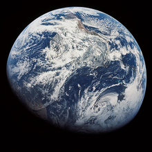 Fotografia da Terra quase totalmente iluminada pelo Sol, exibindo principalmente a cobertura de nuvens sobre o Oceano Atlântico e a América do Sul. A coloração azul dos oceanos domina a imagem.