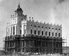 An old photo of the St. George Temple. The upper half is covered in a white plaster, the bottom half is exposed sandstone brick. Workers can be seen on the scaffolding, which is on the lower half.