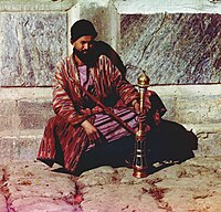 Mann fra Sentral-Asia med tradisjonell kaftan og vannpipe (narghile)