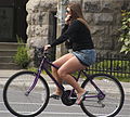 Жена вози велосипед носејќи џемпер и мини здолниште во Канада.