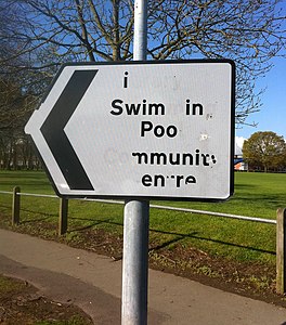 Vandalismo su di una segnaletica stradale nel Regno Unito, che recita: “i Swim in Poo”
