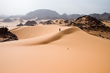 آثار مشي أحد الأشخاص على كُثبان الرِّمال الناعمة في جبال أكاكوس، وهي إحدى المناطق الصحراويَّة الواقعة في غرب ليبيا، وتُشكِّلُ جُزءًا من الصحراء الكُبرى