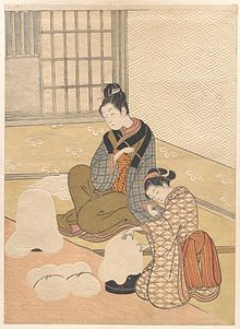 Bản in màu của hai phụ nữ Nhật ăn mặc trang trọng bên lò sưởi. Giấy dán tường và các vật dụng khác được dập nổi rộng rãi.