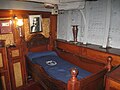 Kajüte des Kapitäns mit Bild von Miguel Grau. Das runde Gerät an der Decke ist keine Lampe, sondern der von Grau angebrachte, vom Bett aus ablesbare Kompass.[5]