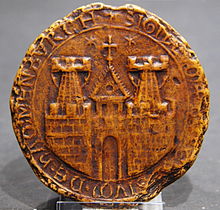 一枚圆形印章，描绘了一座城镇的城墙，城墙上有两座塔楼和一座城门，以及一座教堂的塔楼