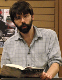 Un homme barbu tenant un livre.
