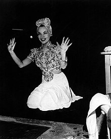 A smiling Miranda, in costume, holds up her hands after leaving her prints outside Grauman's Chinese Theatre.