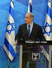 Die Israeliese premier Benjamin Netanyahu omring deur Israeliese vlae in die Eerste Minister se kantoor