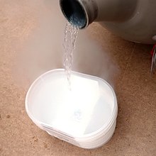 A transparant liquid, with visible evaporation, being poured into a beaker