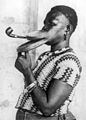 Мадам Густика из «племени пластиногубчатых» курит трубку с удлинённым мундштуком. Нью-Йорк, 1930 год.