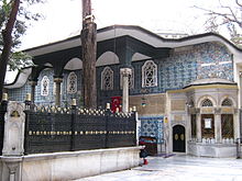 Bangunan dua lantai yang berdindingkan ubin biru Iznik, dengan prostyle portico dan jendela di lantai teratas